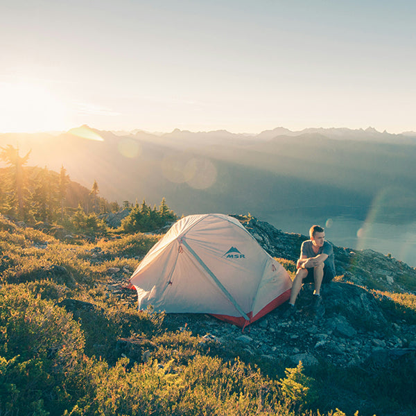 camping zelte von flux perfect, mann mit zelt auf einem berg, see im hintergrund