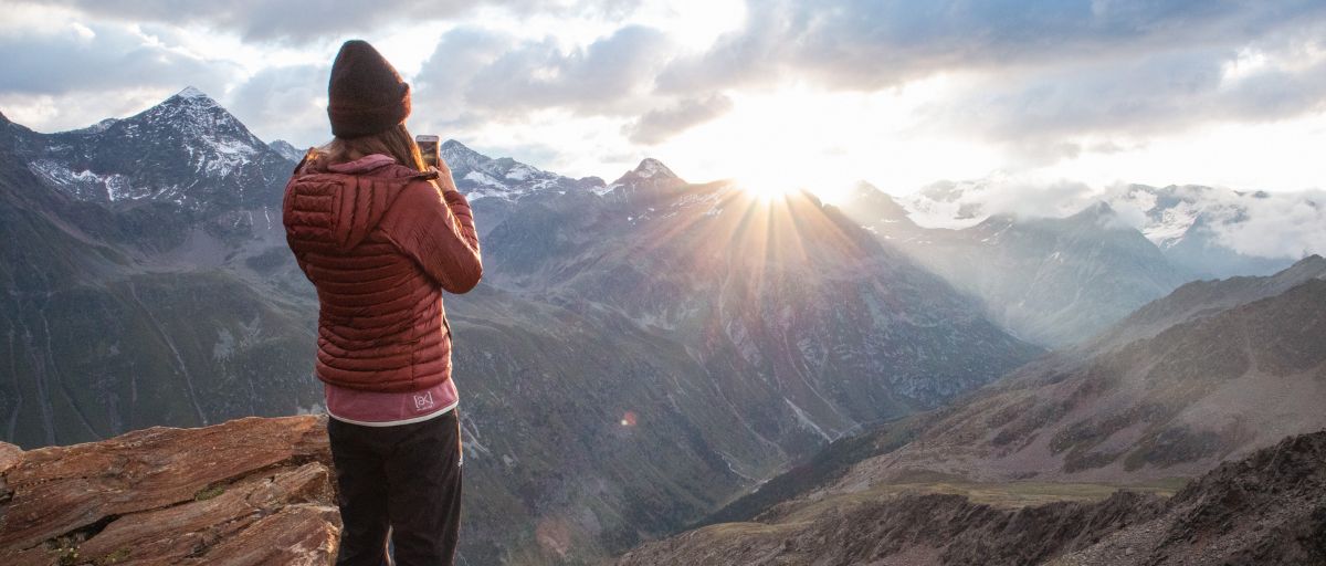 Packliste Wanderurlaub - Frau blickt in den Bergen auf Sonnenuntergang