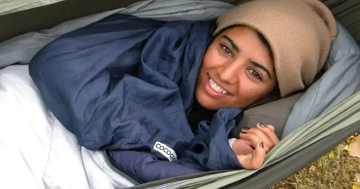 Frau liegt in einem Hammock, mit ihrer Cocoon Decke, bereit für ein Outdoor Abenteuer.