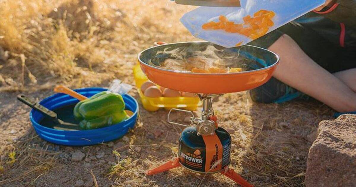Jetboil Camping Equipment im Einsatz - Dame gibt geschnittenes Gemüse in die Pfanne, im Hintergrund ist weiteres Jetboil Outdoor Equipment zu sehen