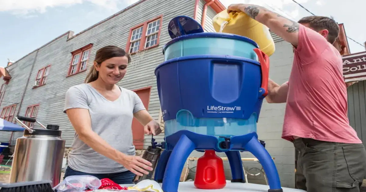 2 Frauen filtern Wasser mit einem LifeStraw Kanister - Sie füllen es in Flaschen ab, bereit für das Outdoor Equipment.