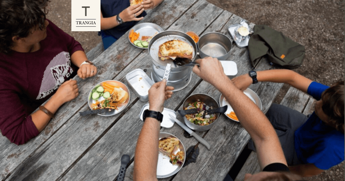 Eine Gruppe versammelt um den Camping Tisch - Kochen und Essen von ihrem Trangia Outdoor Equipment