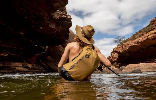 Wanderer durchquert Fluss mit Sea to Summit Dry Bag – robuste Campingausrüstung & Zubehör für Outdoor-Touren