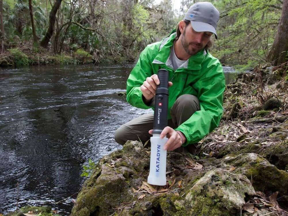 Hier ist der Wasserfilter – Katadyn – Combi Microfilter Plus – inkl. Wasserhahn-Kit im Einsatz - ein Mann füllt das gefilterte Wasser in seine Trinkflasche